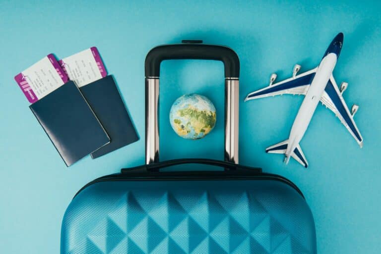 top view of globe and plane models, travel bag and passports with tickets on blue background